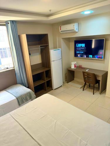 里约热内卢Studio Premium Flamengo的一间卧室配有一张床、一张书桌和一台冰箱