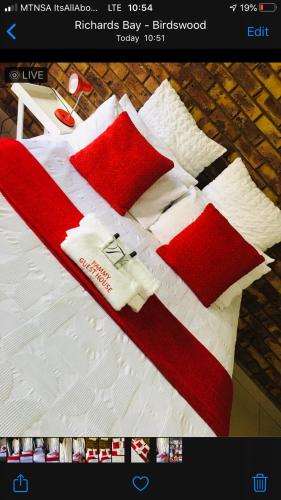 理查兹湾Pammy Guest House的一张带红白毯子和枕头的床