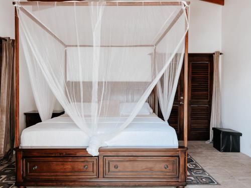 苏弗里耶尔Moringa Villa Master Suite的卧室配有带白色床单的天蓬床