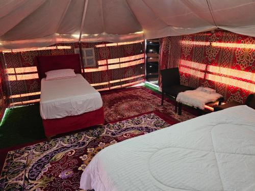 BadīyahMoon Light Camp的一间卧室配有两张床,帐篷内配有椅子