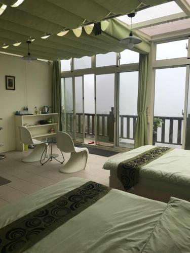 三义云庭兰园的一间卧室设有两张床、一张桌子和窗户。