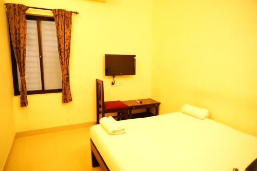 库姆巴科纳姆sitthi residency的一间卧室设有一张床、一个窗口和一把椅子