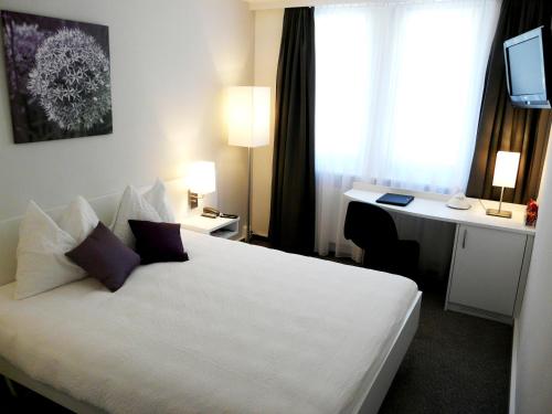 特湾Fontana Budget的一间酒店客房,配有一张白色的床和一张书桌