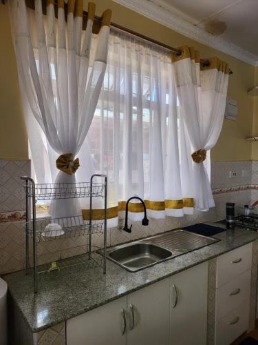 埃尔多雷特G&G Homes Eldoret的厨房配有白色窗帘、水槽和窗户