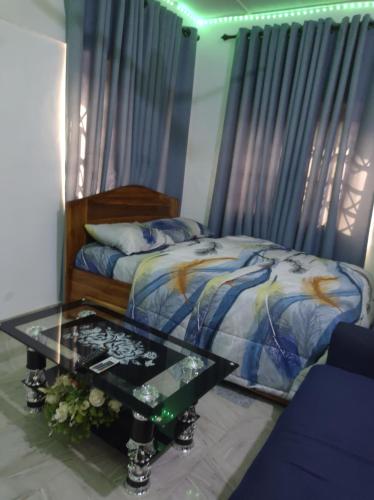 SunyaniKingee Lodge的一间卧室配有一张床和一张玻璃桌
