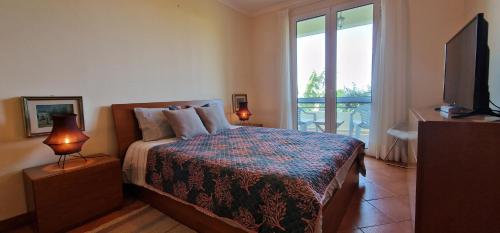 阿科达卡列塔Sunny Arco Retreat的一间卧室设有一张带电视的床和一个阳台。