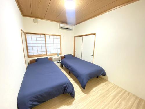 奄美島の宿　結んちゅ的配有蓝色床单的客房内的两张床