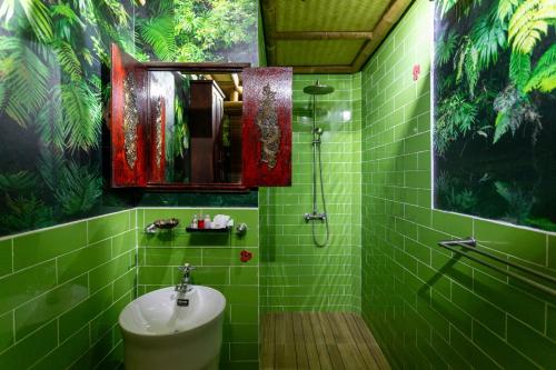 北碧The Parrot Inn Kanchanaburi的绿色瓷砖浴室设有水槽和淋浴