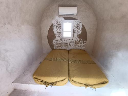 Qaşr GhīlānL'Oasis的一个小房间的一个床位,设有窗户