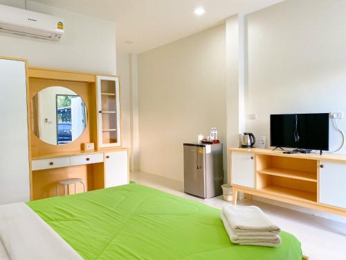Ban Muang Baบ้านพักสิริ มุกดาหาร (Baan Siri Mukdahan)的一间卧室配有绿色的床和电视