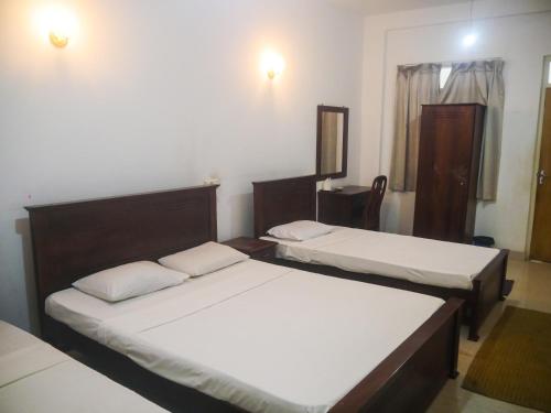 卡特勒格默Visaka Hotel - Kataragama的一间卧室配有两张床和镜子