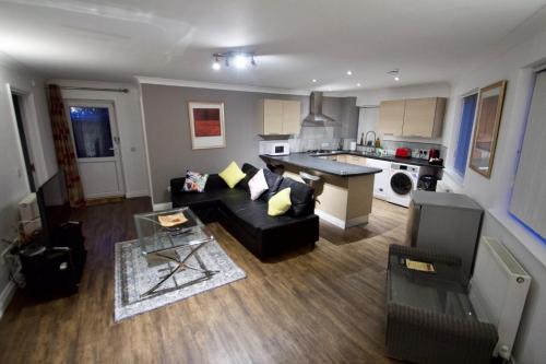 纽伯里Mill Lane Refurbished 2 Bedroom Apartment的一间带黑色沙发的客厅和一间厨房