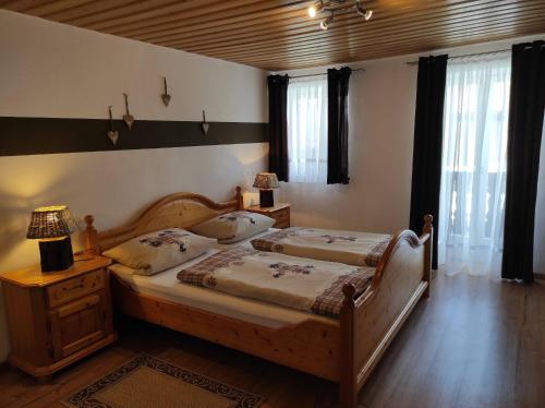柯尼希斯湖畔舍瑙Gästehaus Vorderwahllehen的一间卧室设有两张床和一个床头柜及窗户。