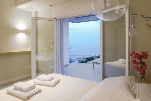 Monolia蒙诺利亚度假屋的卧室配有白色的床和大型玻璃窗。