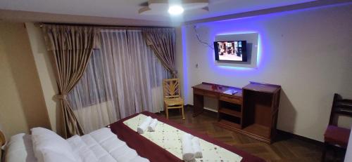 奥塔瓦洛Hospedaje La Joya的一间卧室配有一张床、一张书桌和一台电视