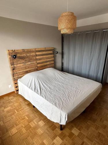 马赛Appartement spacieux bien situé的卧室配有白色的床和木制床头板