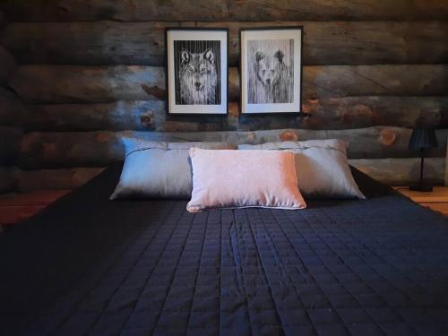 库萨莫Lumi - kelohirsimökki Rukalla, log cabin at Ruka的卧室配有一张墙上三幅照片的床