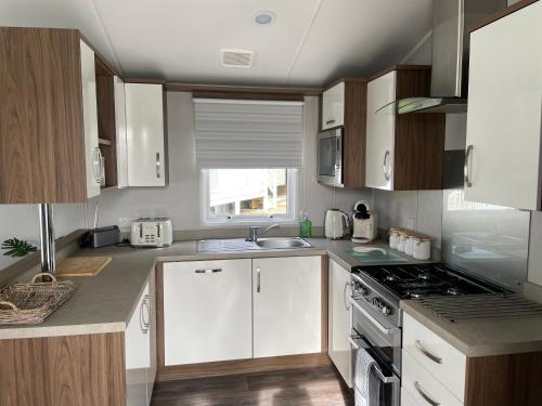 Belton6 Berth Comfy Homely Caravan, Dog Friendly的厨房配有白色橱柜和炉灶烤箱。