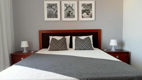 波尔蒂芒Rocha Gardens Apartment的一间卧室配有一张带两盏灯的床,墙上挂有图片