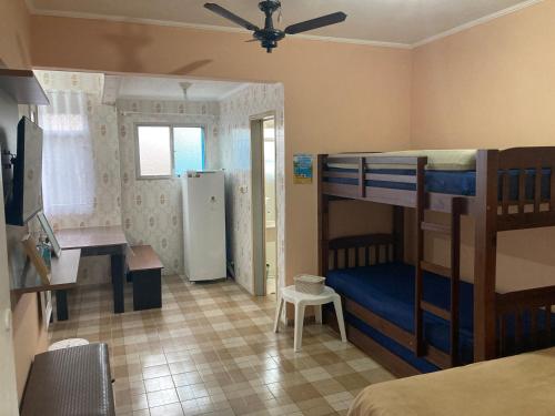 蒙加瓜Kitnet Cantinho 26的一间卧室配有双层床、一张书桌和一台冰箱