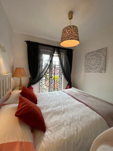 丁格尔Tig Monbretia的卧室配有白色的床、红色枕头和窗户