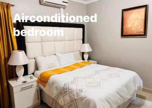 姆巴巴内GoldenWays Apartment 3的一间卧室配有一张带白色床罩和两盏灯的床。