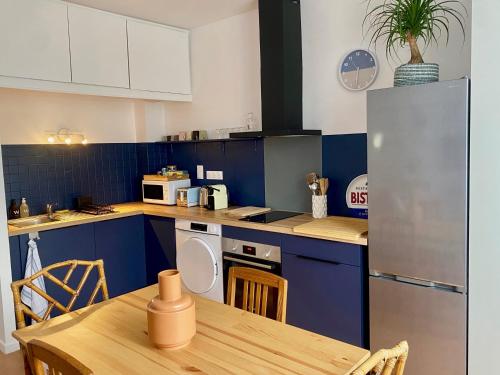 苏瓦松Le Central - Coeur historique - Netflix/Disney+的厨房配有蓝色橱柜和木桌