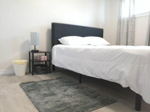 埃德蒙顿Sweethome - 10 min to Rogers Place & so much more的卧室配有一张带白色床单和地毯的大床。