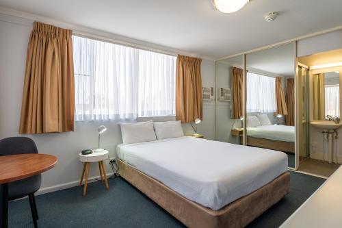 麦夸里港阿罗哈港口汽车旅馆的酒店客房配有一张床铺、一张桌子和一张书桌。