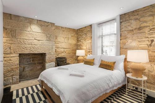 悉尼Elegant Paddington Sandstone Cottage with Parking的一间卧室设有一张大床和石墙