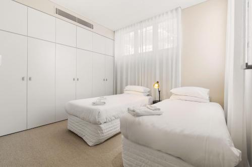 悉尼Bondi Oasis: 2BR + Balcony Bondi Beach的白色墙壁客房的两张床