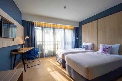 勒吉安Solia Legian Bali的酒店客房设有两张床、一张书桌和窗户。