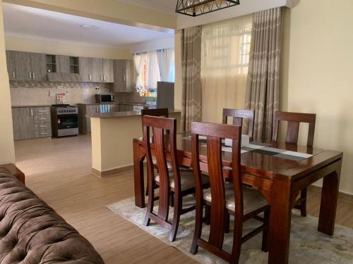 Kitengela Happy home from home的厨房以及带木桌和椅子的用餐室。