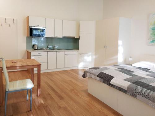 维也纳Riess City Rooms - Self Check-in的一间卧室配有一张床铺和一张桌子,还设有一间厨房