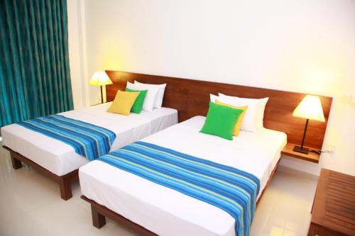卡特勒格默桑维尔旅游度假村的两张位于酒店客房的床,配有绿色和蓝色枕头