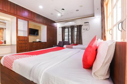 钦奈OYO Flagship Maheshwari Villas的一间卧室配有一张带红色和白色枕头的大床