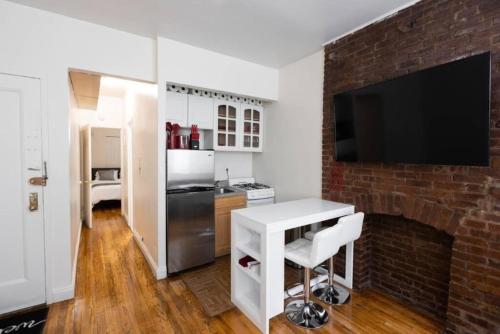 纽约Warm 1-Bedroom Apt in Manhattan的厨房设有砖砌壁炉和白色桌子。
