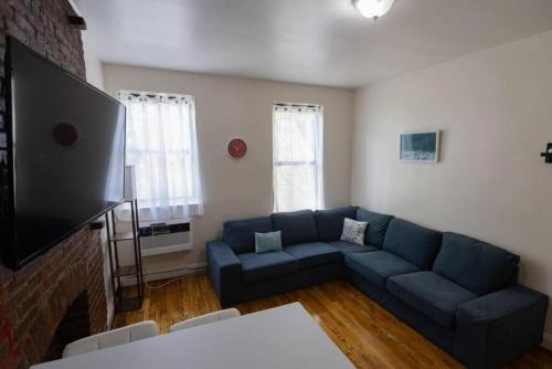 纽约Warm 1-Bedroom Apt in Manhattan的客厅配有蓝色的沙发和电视