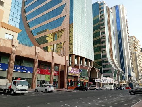 迪拜Marbella Holiday Homes - Al Nahda 2BHK的一条城市街道,汽车停在高楼前