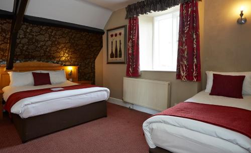 伯德利普Royal George Hotel by Greene King Inns的一间卧室设有两张床和窗户。