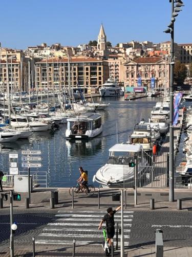 马赛T4 Marseille Vue imprenable sur Vieux Port的骑着自行车的人在码头旁边乘船