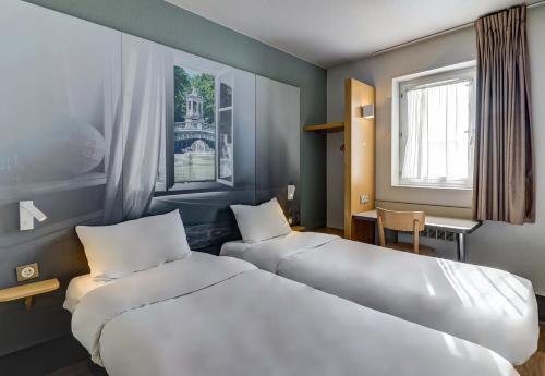 第戎B&B HOTEL Dijon Nord Zénith的酒店客房设有两张床和窗户。