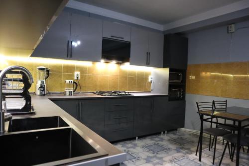 埃里温Sweet Sleep hostel的厨房配有黑色橱柜、水槽和桌子