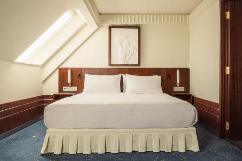 巴黎Hôtel Des Grands Voyageurs的卧室配有一张白色大床和天窗