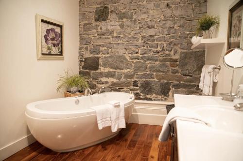魁北克市皇家达尔豪斯酒店的浴室配有白色浴缸和石墙