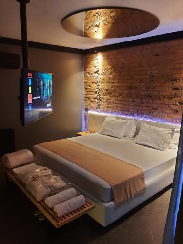 南卡希亚斯LUV Gardens Motel - Adults Only的一间卧室设有一张大床和砖墙