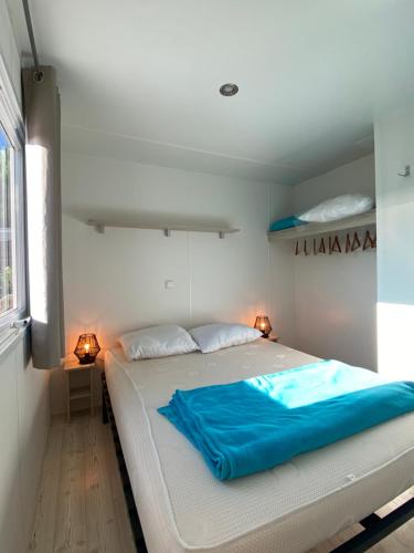 鲁西隆地区卡内Mobil-home 5 personnes dans camping Mar Estang 4 étoiles avec accès à la plage的卧室配有一张大白色的蓝色床单
