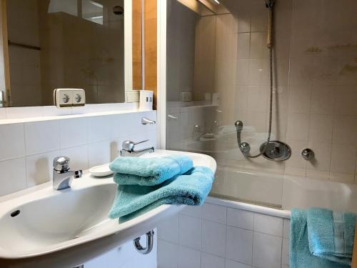 博登湖畔克雷斯波洛Ferienwohnung Alina的浴室配有水槽和带蓝色毛巾的淋浴