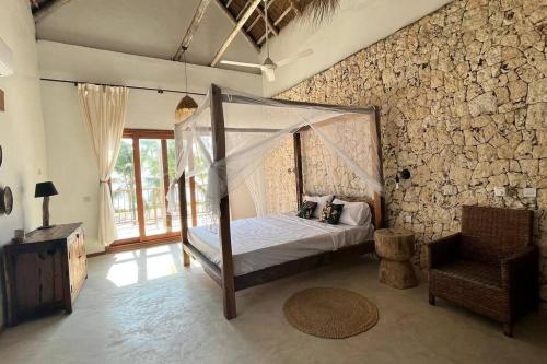 平圭Ocean Front Villa with pool, Zanzibar的卧室配有一张石墙天蓬床
