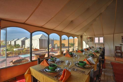梅尔祖卡Golden Camp & Oasis的一间带长桌和大窗户的用餐室